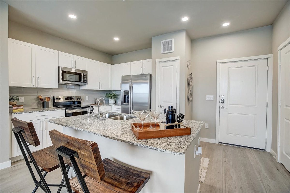 Bright kitchen with quartz island seating, double sink, and stainless appliances at Skyview North.
